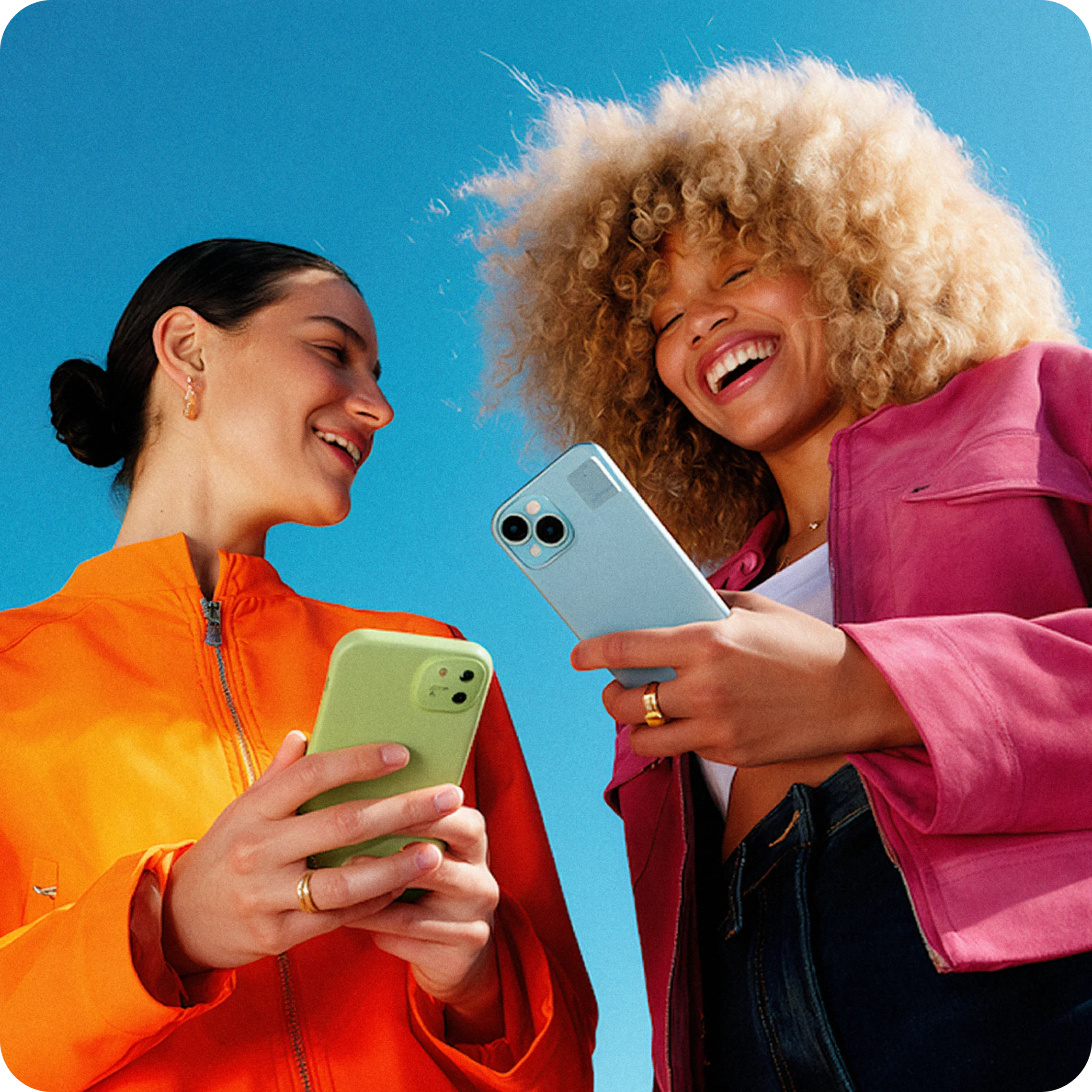 Two friends laughing while looking at their phones
